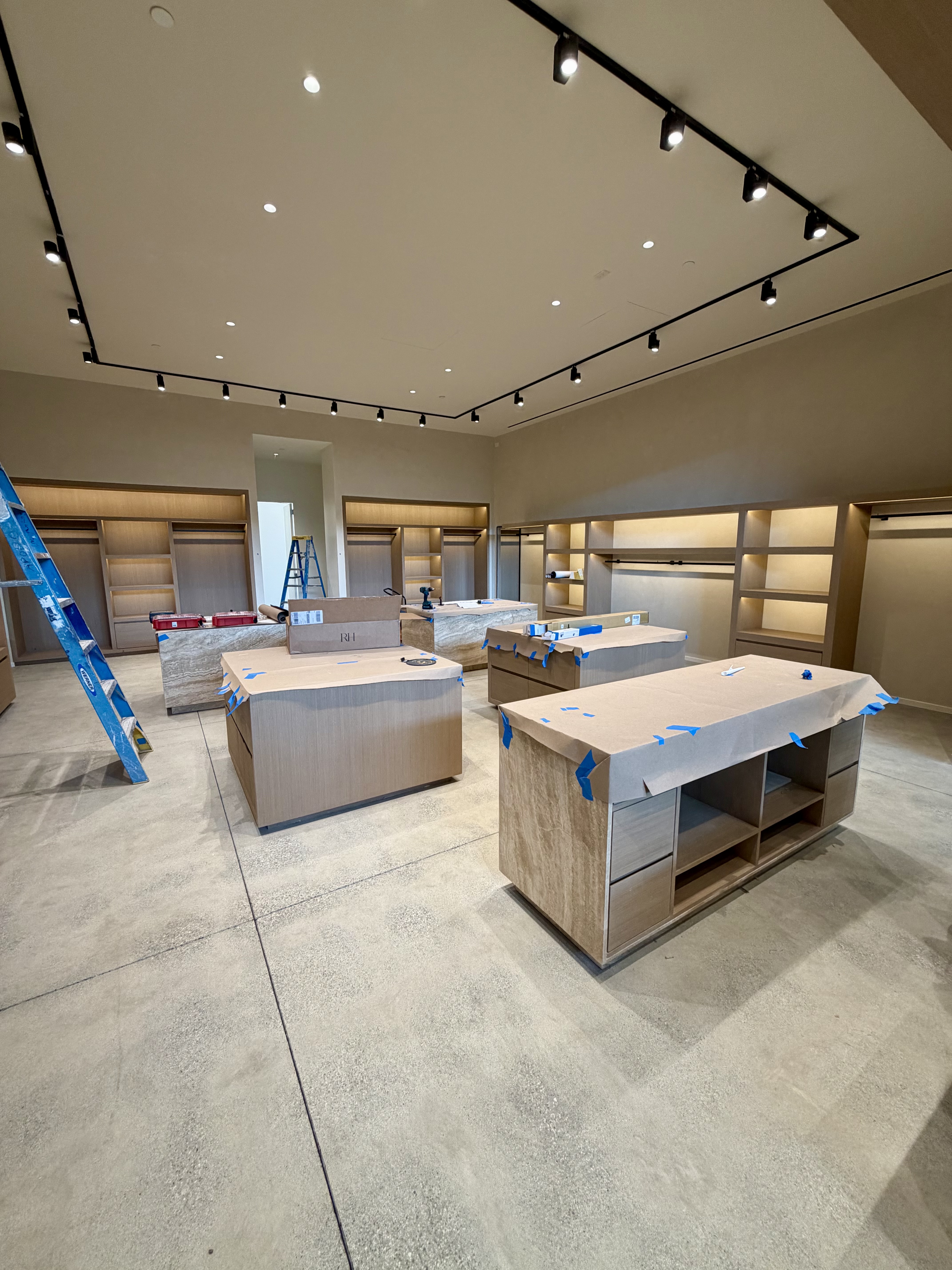 Wide view of the Malibu boutique before merchandising, with unfinished fixtures and ladders