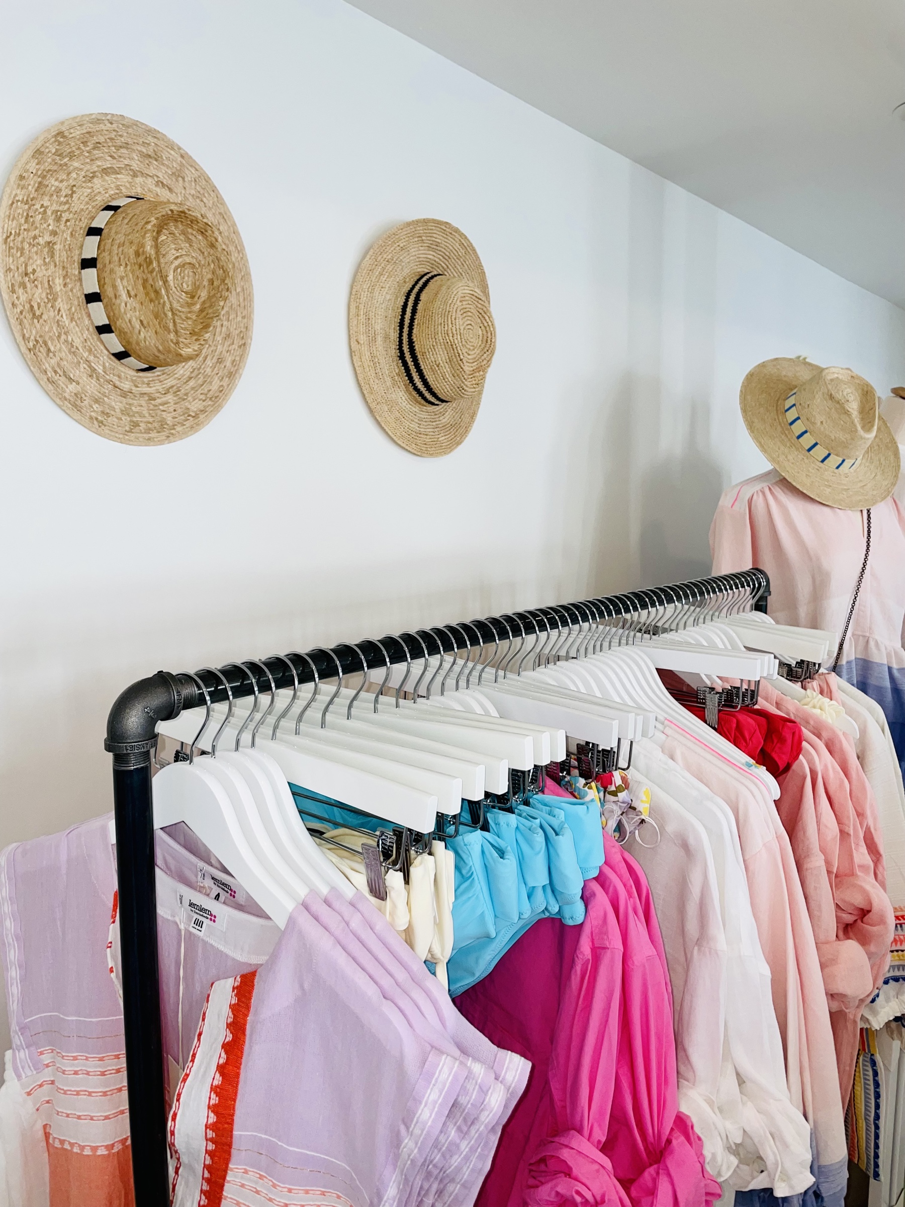 Martha’s Vineyard boutique apparel rail with pastel resort pieces and straw hats