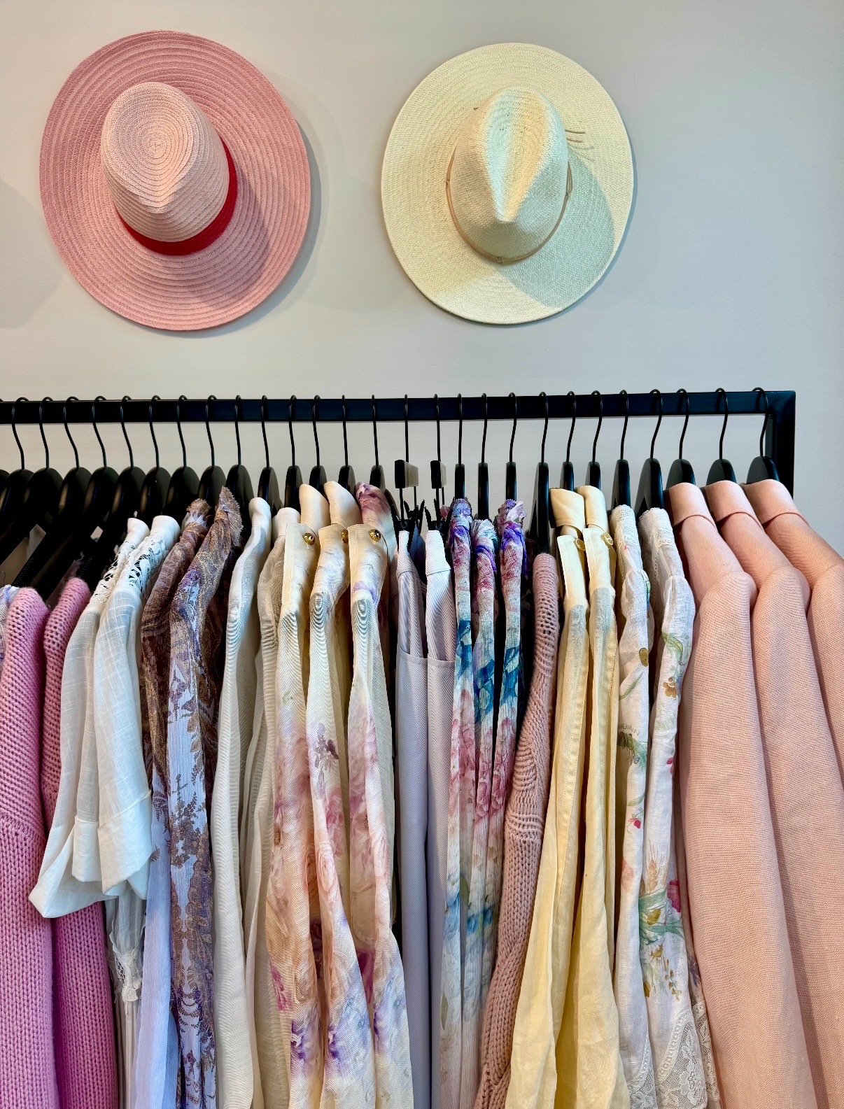 Pastel pink, ivory, and patterned apparel arranged beneath coordinating hats in Nantucket